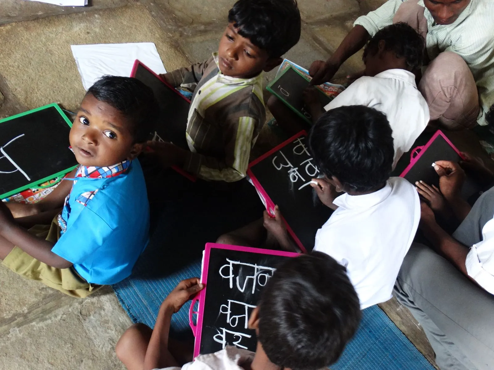 Young children writing on slates in a village school