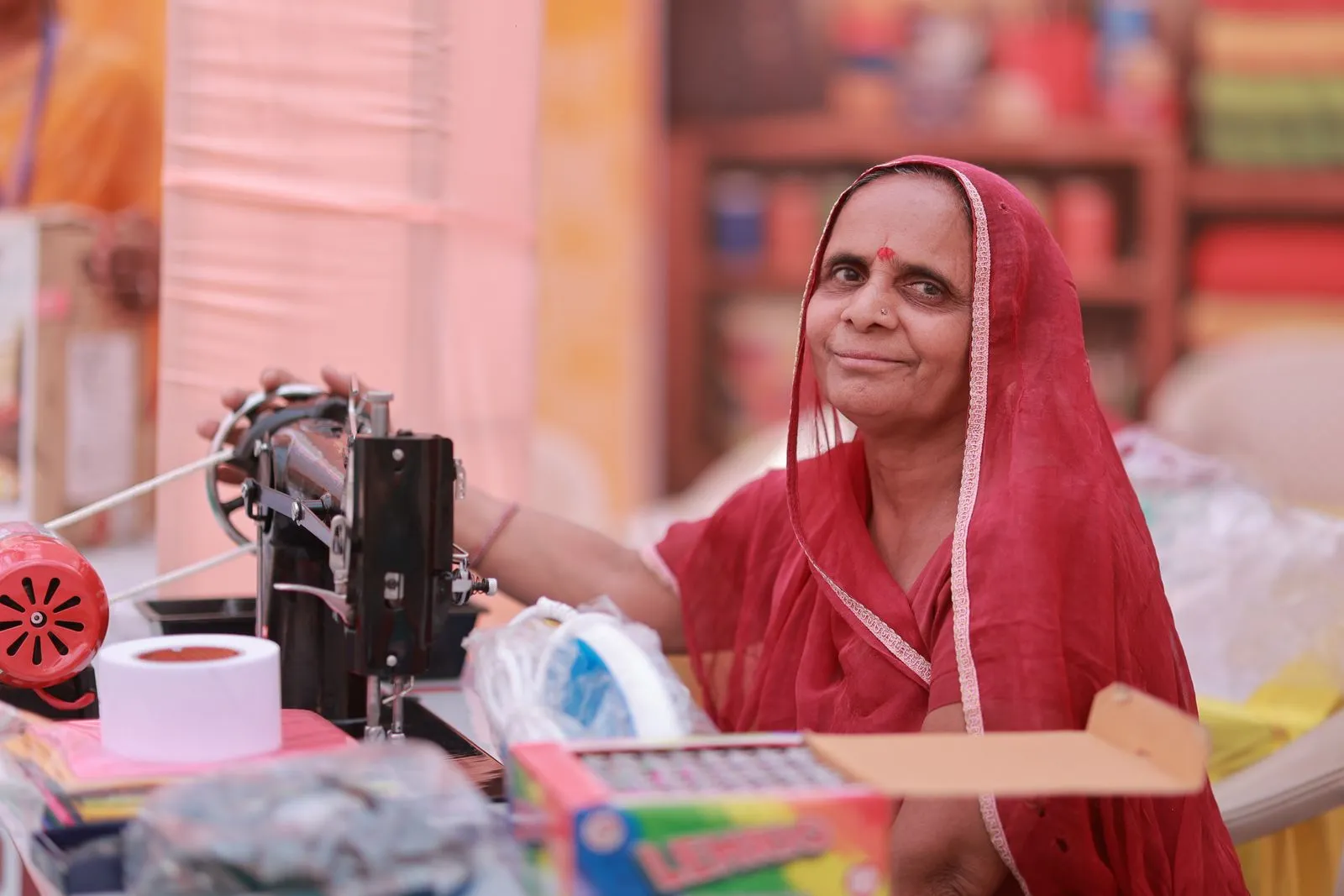 A woman in a red sari at her sewing machine in Rajasthan