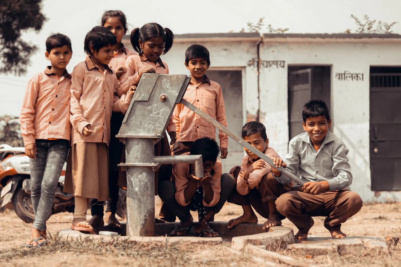 Children gathered around a village hand pump