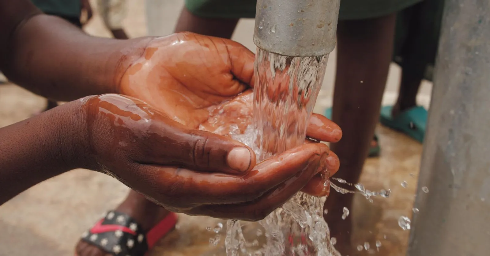 Hands catching water from a pump
